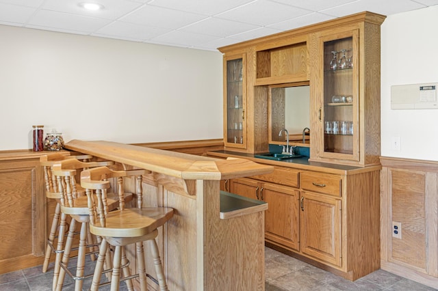 bar featuring sink, a drop ceiling, and light tile patterned flooring