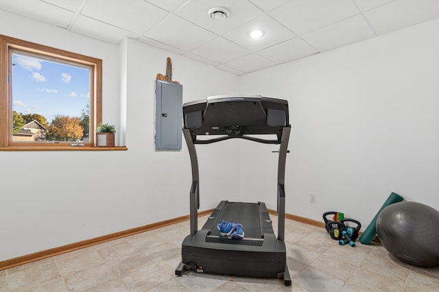 exercise room with a paneled ceiling, electric panel, and tile patterned flooring