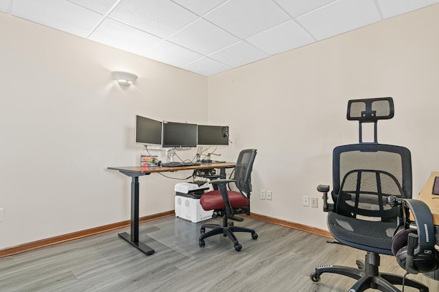 home office with light hardwood / wood-style floors and a drop ceiling