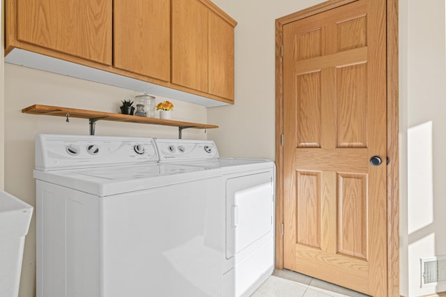 washroom featuring washer and dryer, cabinets, and light tile patterned floors