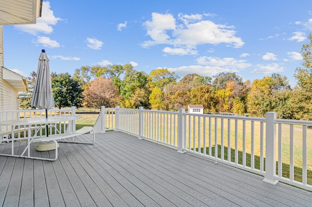 wooden deck with a storage shed and a lawn