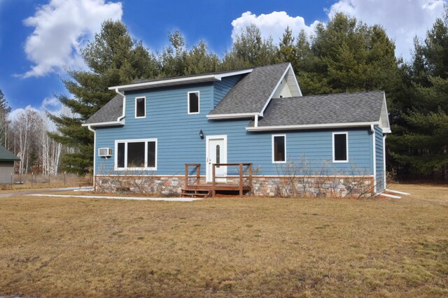 rear view of property featuring a lawn, a wall mounted AC, and roof with shingles