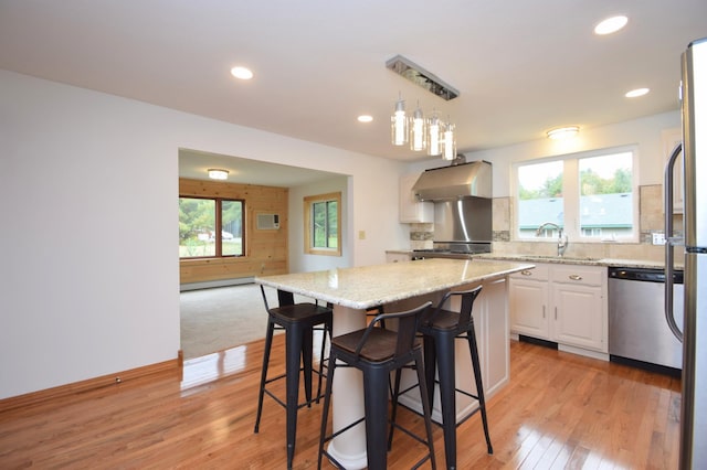 kitchen with dishwasher, a wealth of natural light, light wood-style flooring, exhaust hood, and a baseboard radiator