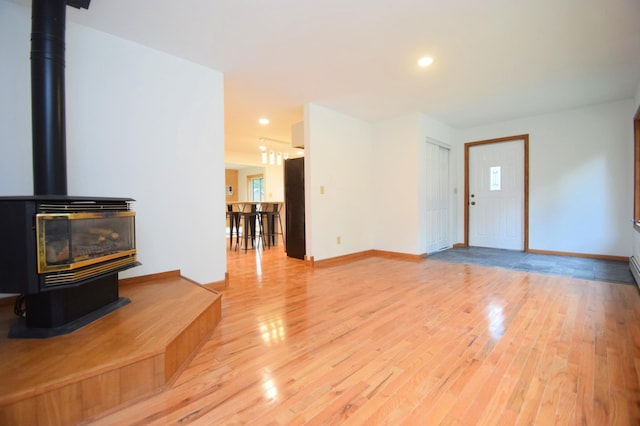 living area with a wood stove, baseboards, and light wood finished floors