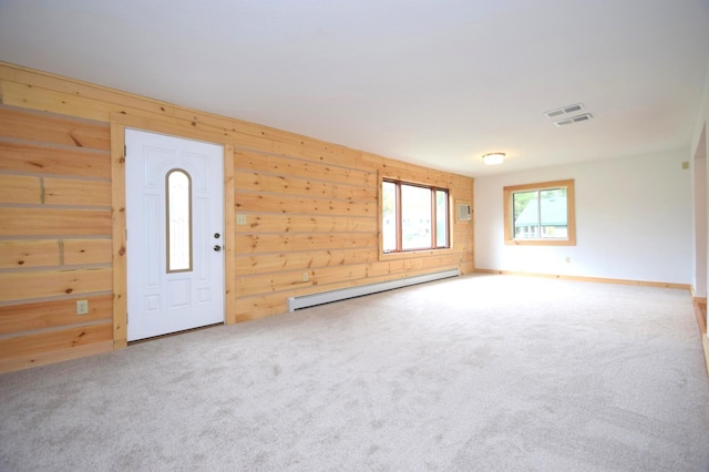 interior space featuring visible vents, baseboard heating, wood walls, and carpet