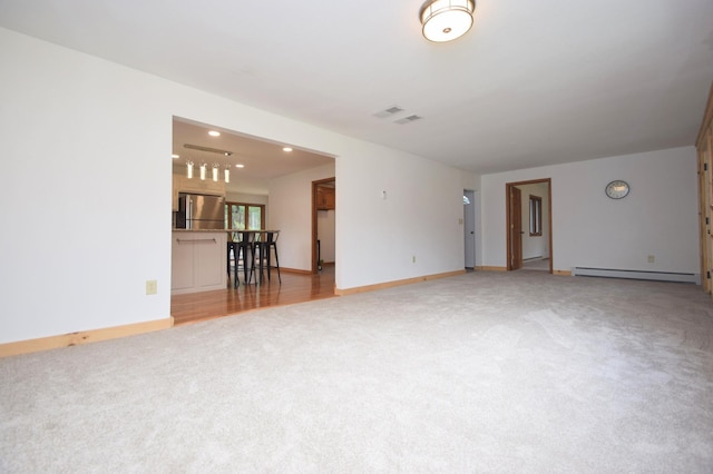 unfurnished living room featuring visible vents, light carpet, a baseboard heating unit, recessed lighting, and baseboards