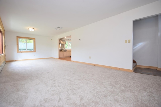 spare room featuring stairs, visible vents, light colored carpet, and baseboards