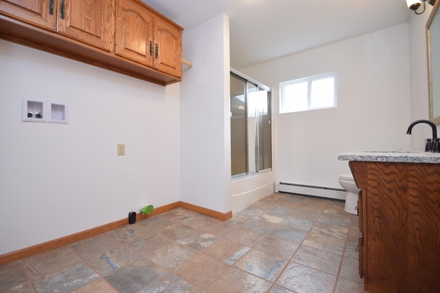 laundry room with hookup for a washing machine, baseboards, a sink, stone finish flooring, and a baseboard heating unit