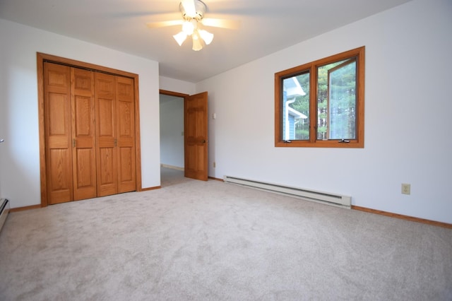 unfurnished bedroom featuring light carpet, baseboards, a baseboard heating unit, and a closet