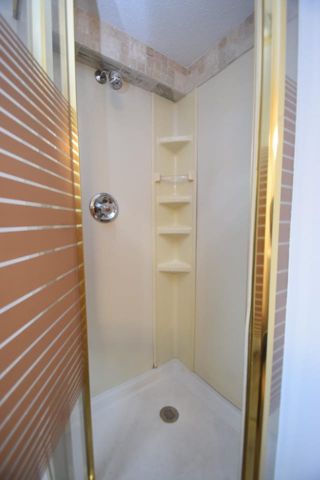 full bathroom with a shower stall and a textured ceiling