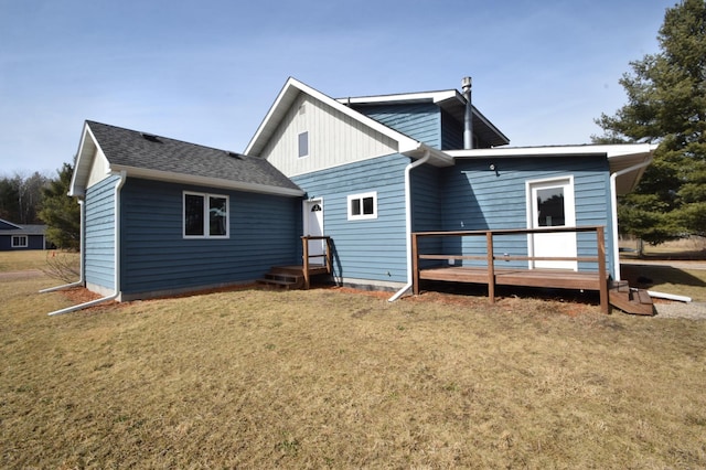 back of property featuring a yard and roof with shingles