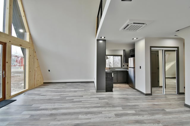 unfurnished living room featuring light wood-type flooring, sink, and plenty of natural light