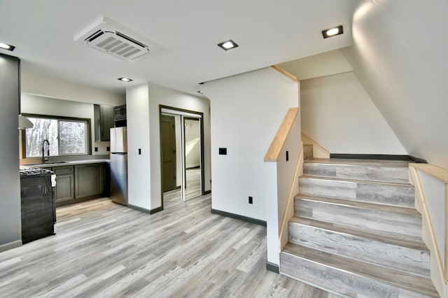 stairway with hardwood / wood-style floors and sink