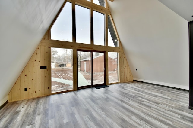 additional living space featuring wood walls, light wood-type flooring, and vaulted ceiling