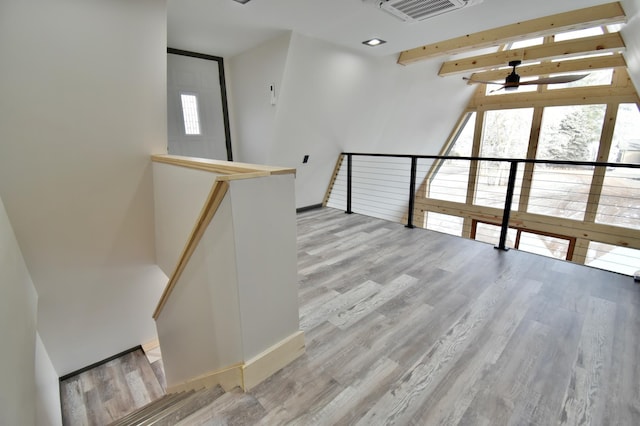 interior space with ceiling fan, wood-type flooring, and beamed ceiling