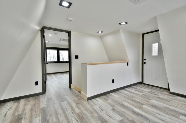 empty room featuring light hardwood / wood-style floors, lofted ceiling, and a wealth of natural light