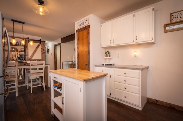 kitchen with a kitchen island, butcher block counters, a barn door, white cabinetry, and dark hardwood / wood-style flooring