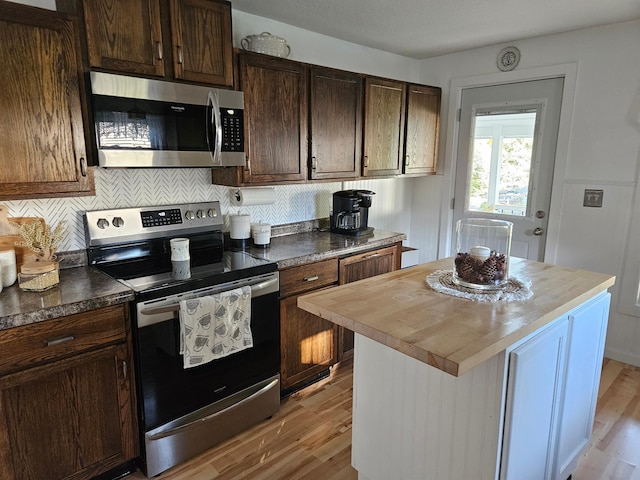 kitchen featuring dark brown cabinets, stainless steel appliances, light hardwood / wood-style floors, a center island, and butcher block countertops