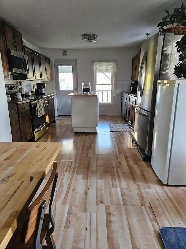 kitchen with light hardwood / wood-style floors, appliances with stainless steel finishes, a textured ceiling, and dark brown cabinets