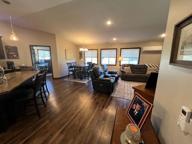 living room with a notable chandelier, sink, dark wood-type flooring, and an AC wall unit