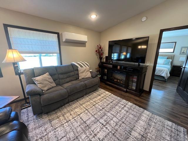 living room with lofted ceiling, hardwood / wood-style flooring, and a wall mounted AC