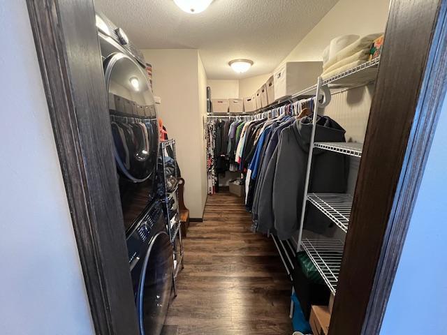 interior space with a textured ceiling, stacked washing maching and dryer, and dark hardwood / wood-style flooring