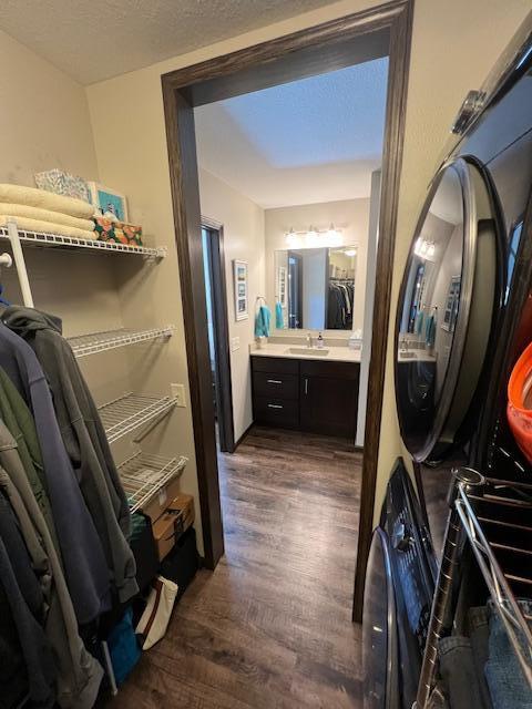 clothes washing area featuring sink, stacked washer and dryer, and dark wood-type flooring