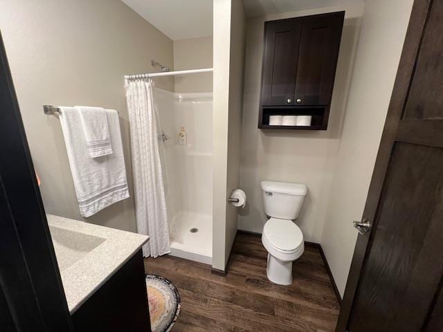 bathroom featuring hardwood / wood-style flooring, toilet, walk in shower, and vanity