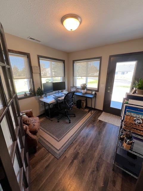 office space with a textured ceiling, plenty of natural light, and dark hardwood / wood-style flooring