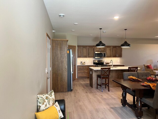 3106 Bassett Dr, Mankato, MN 56001 - kitchen with light wood-style flooring, stainless steel appliances, a kitchen breakfast bar, backsplash, and light countertops