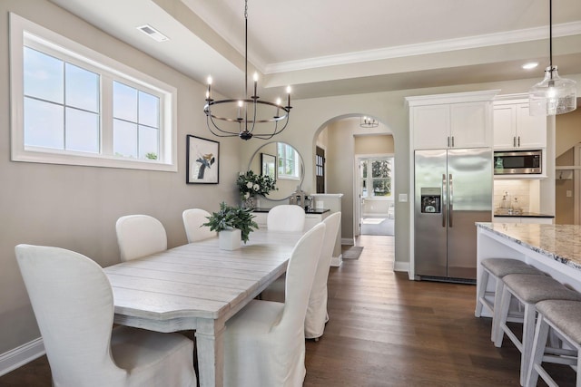 dining space featuring arched walkways, a wealth of natural light, ornamental molding, and dark wood finished floors