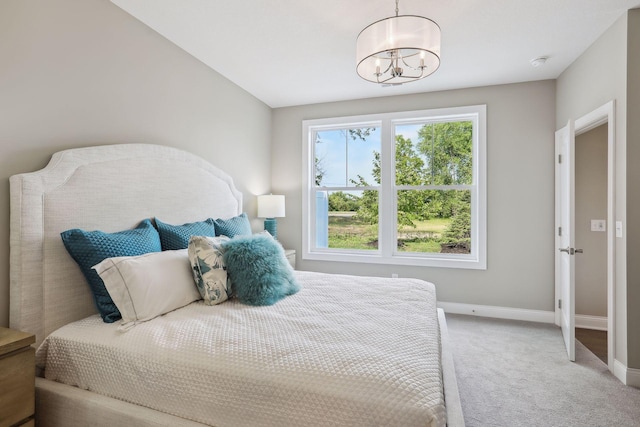 bedroom with a chandelier, light carpet, and baseboards
