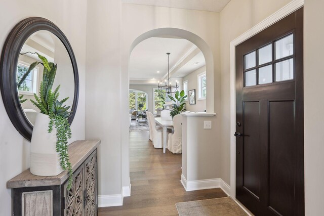 foyer entrance with baseboards, recessed lighting, dark wood finished floors, arched walkways, and a notable chandelier