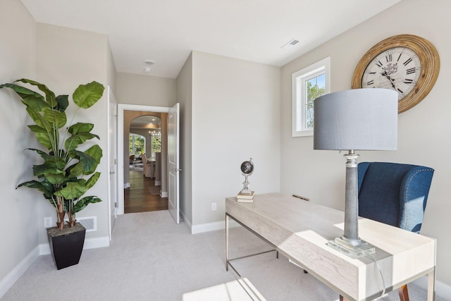 carpeted office space with arched walkways, baseboards, and visible vents