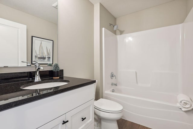 full bath with toilet, wood finished floors, vanity, and washtub / shower combination
