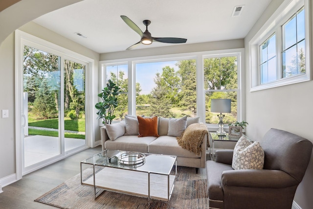 sunroom featuring arched walkways, a healthy amount of sunlight, visible vents, and wood finished floors