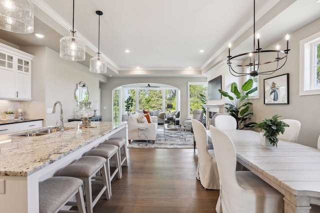 dining space featuring ceiling fan with notable chandelier, recessed lighting, crown molding, arched walkways, and dark wood-style floors