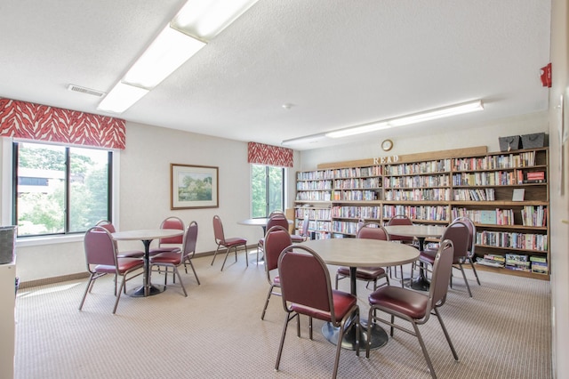 dining space with light carpet and a textured ceiling