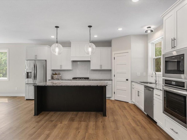 kitchen featuring sink, a kitchen island, light stone counters, and stainless steel appliances