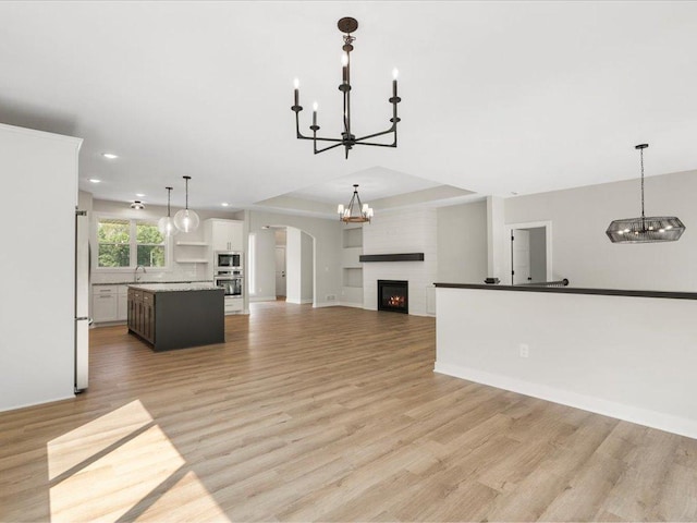 unfurnished living room featuring sink, a large fireplace, and light hardwood / wood-style flooring