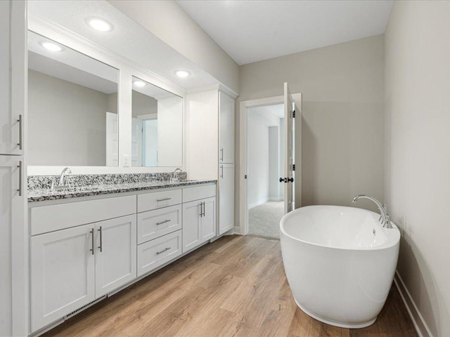 bathroom with vanity, a bathing tub, and hardwood / wood-style floors