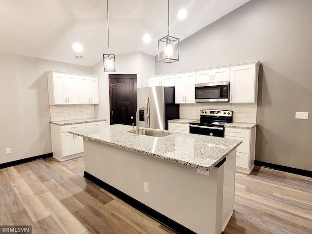 kitchen featuring hanging light fixtures, white cabinets, stainless steel appliances, and a center island with sink