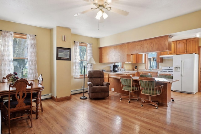 kitchen with white appliances, kitchen peninsula, a kitchen breakfast bar, light hardwood / wood-style floors, and ceiling fan