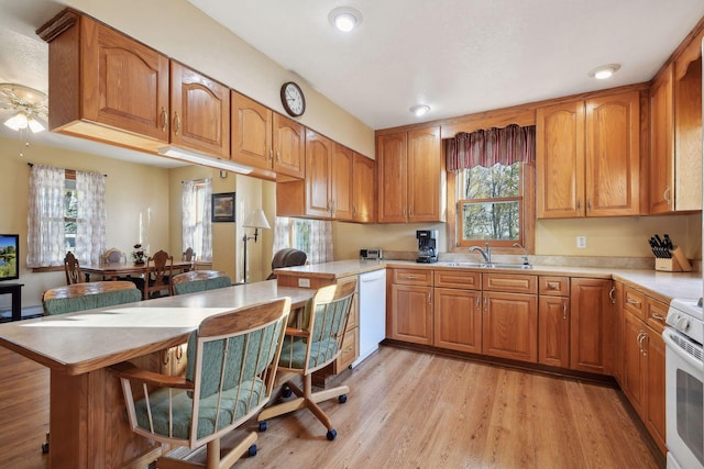 kitchen with light hardwood / wood-style flooring, kitchen peninsula, a kitchen bar, and a wealth of natural light