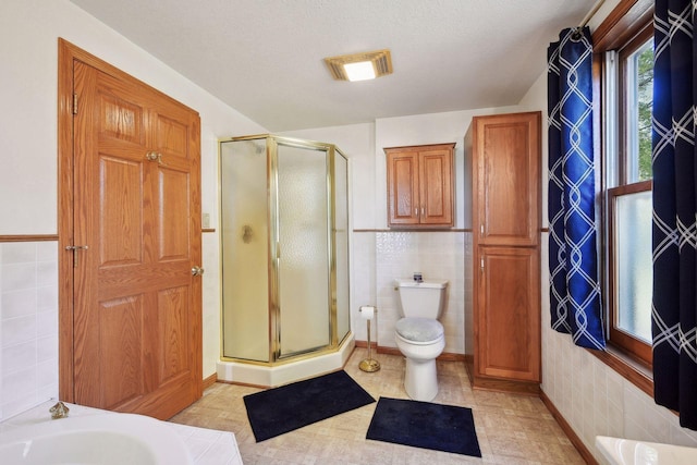 bathroom featuring toilet, tile walls, and plus walk in shower