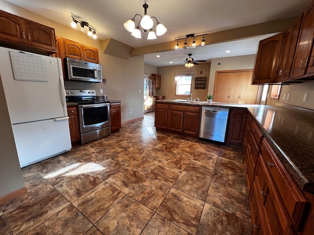 kitchen featuring kitchen peninsula, ceiling fan with notable chandelier, stainless steel appliances, sink, and hanging light fixtures