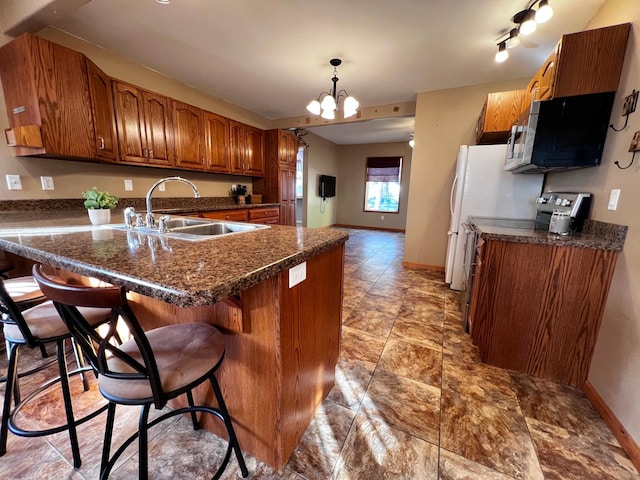 kitchen with a kitchen bar, kitchen peninsula, sink, a chandelier, and hanging light fixtures