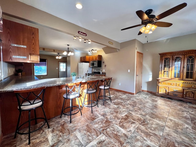 kitchen with kitchen peninsula, a breakfast bar, ceiling fan with notable chandelier, and appliances with stainless steel finishes