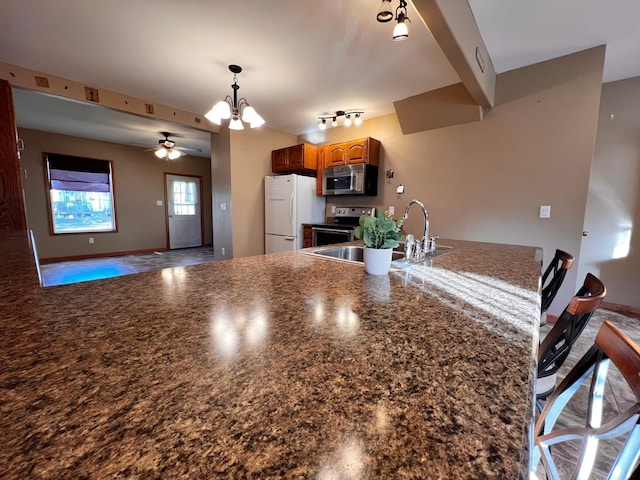 kitchen featuring sink, kitchen peninsula, a breakfast bar, ceiling fan with notable chandelier, and appliances with stainless steel finishes