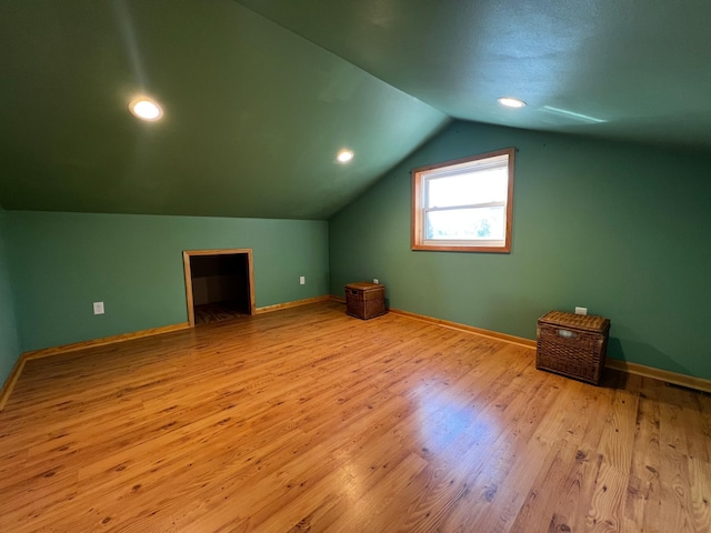 bonus room with lofted ceiling and light wood-type flooring